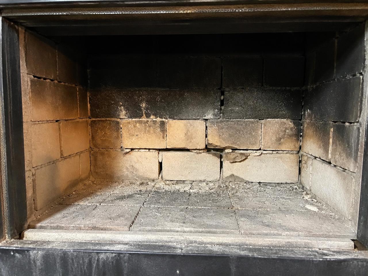 Cracked firebrick and deteriorated mortar inside a fireplace firebox in San Antonio